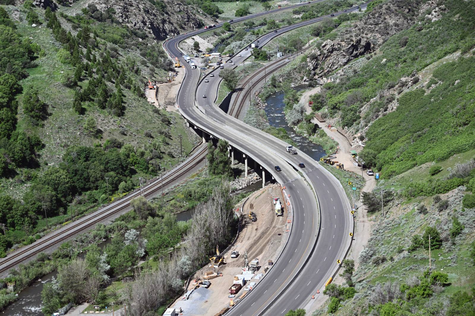 Curved highway under construction running parallel to train tracks